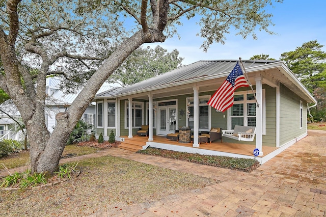 view of front facade featuring metal roof, a porch, and french doors