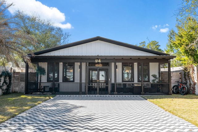 view of front of property with a porch, fence, and a front lawn