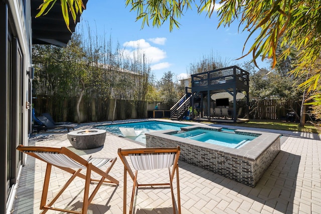 view of pool with a fire pit, a patio, a fenced backyard, stairway, and a pool with connected hot tub