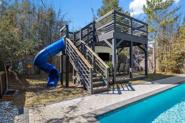 view of play area with fence, a fenced in pool, and a wooden deck