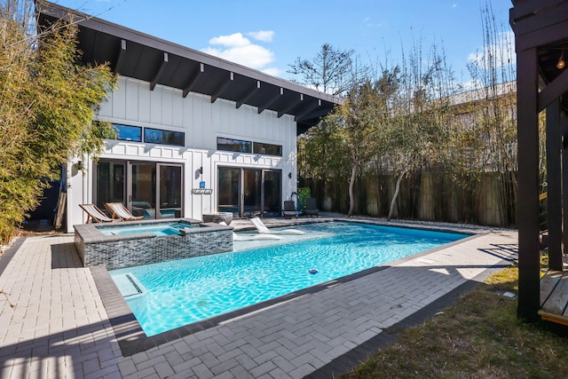 view of pool with a patio, fence, and a pool with connected hot tub