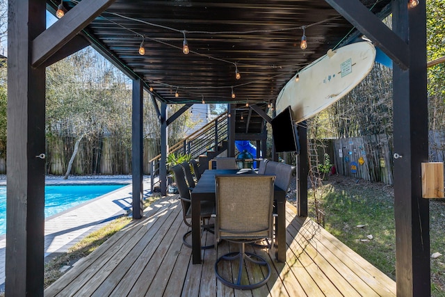 wooden deck featuring outdoor dining area, a fenced backyard, and an outdoor pool