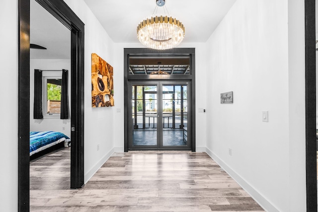 foyer featuring baseboards, wood finished floors, and a notable chandelier