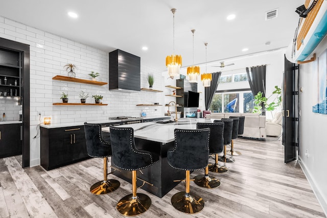 kitchen with light wood-type flooring, visible vents, open shelves, and dark cabinets