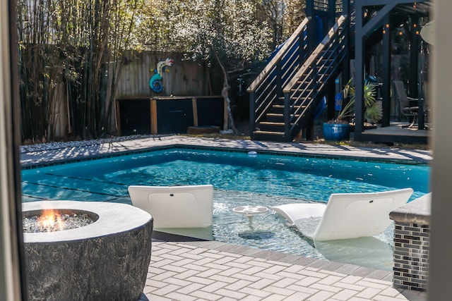 view of swimming pool with a fire pit, fence, stairway, a fenced in pool, and a patio area