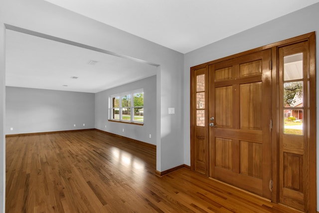 foyer entrance featuring visible vents, wood finished floors, and baseboards