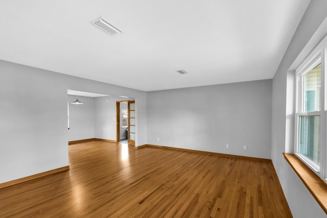 spare room featuring wood finished floors, visible vents, and baseboards