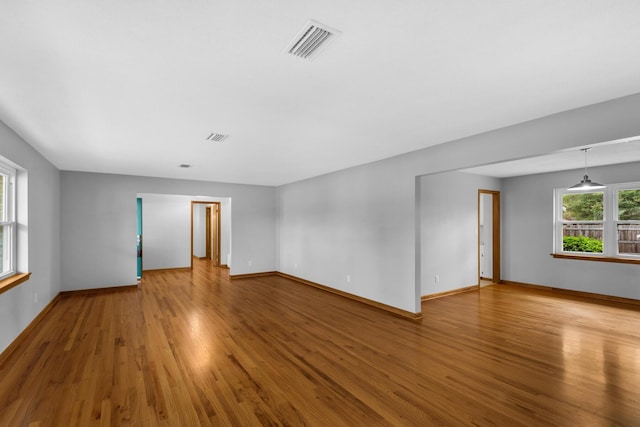 unfurnished room featuring wood finished floors, visible vents, and baseboards