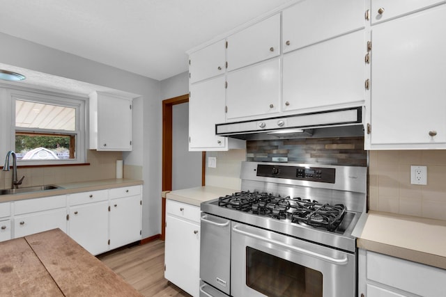 kitchen featuring stainless steel gas range oven, under cabinet range hood, light countertops, and a sink