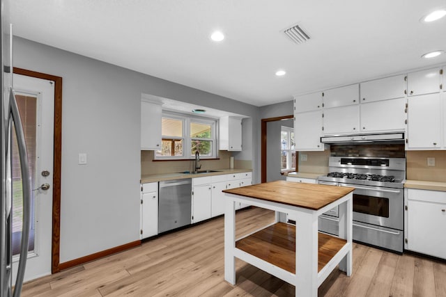 kitchen with visible vents, under cabinet range hood, light countertops, stainless steel appliances, and a sink