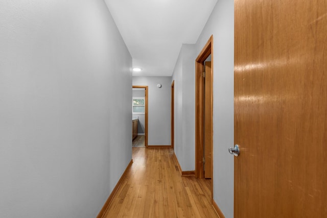 hallway featuring baseboards and light wood finished floors