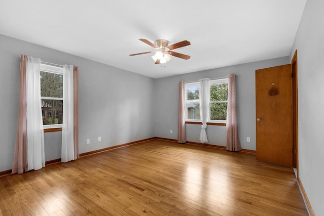 empty room with hardwood / wood-style flooring, a ceiling fan, and baseboards