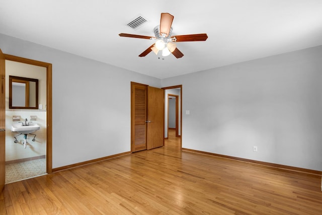 unfurnished bedroom featuring visible vents, baseboards, ensuite bathroom, light wood-style floors, and a closet