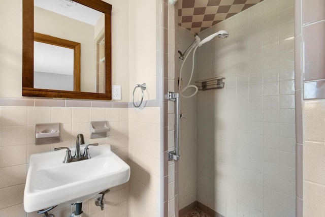 full bathroom with a shower stall, tile walls, and a sink