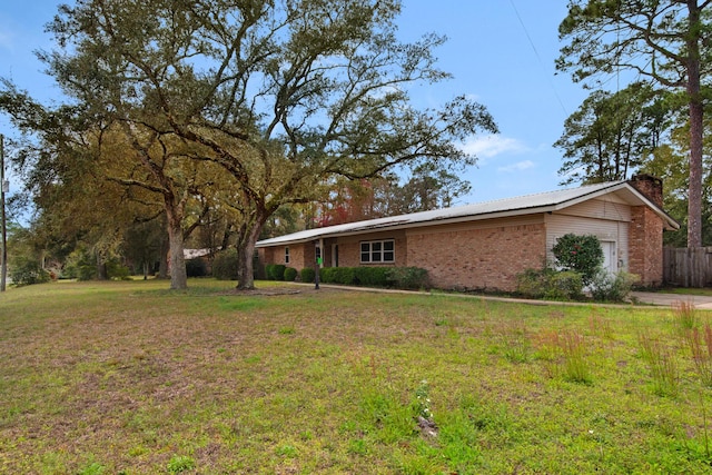 view of front facade with fence, an attached garage, a chimney, a front lawn, and brick siding