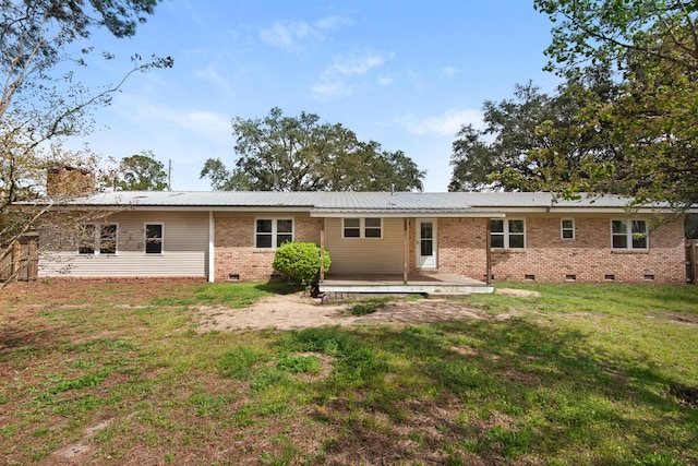 rear view of property featuring brick siding, a lawn, metal roof, a deck, and crawl space