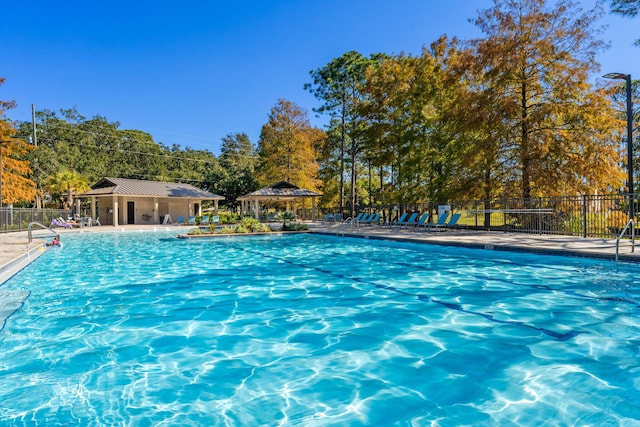 community pool with a patio area, fence, and a gazebo