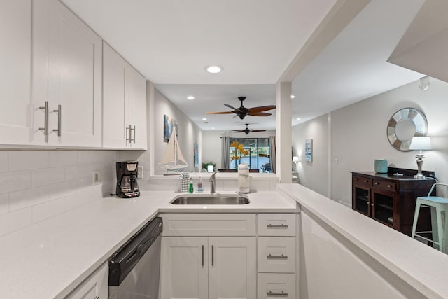 kitchen with light countertops, decorative backsplash, stainless steel dishwasher, white cabinets, and a sink