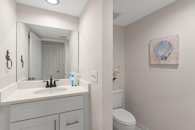 half bathroom with vanity, toilet, and baseboards