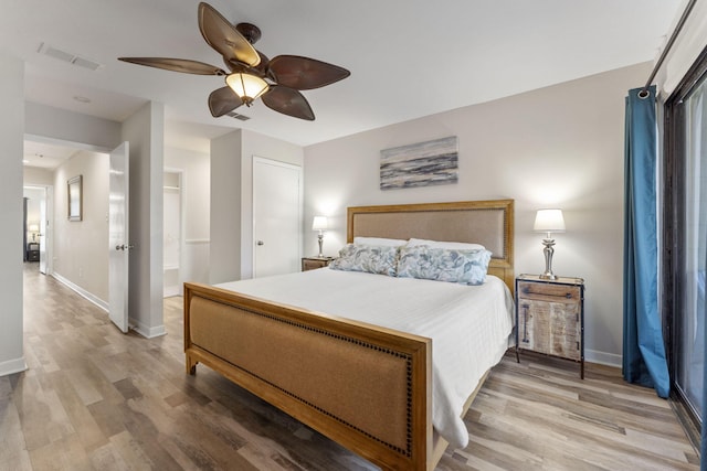 bedroom featuring light wood-type flooring, baseboards, visible vents, and ceiling fan