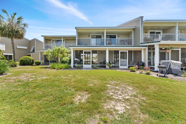 back of house with a balcony, a sunroom, and a yard