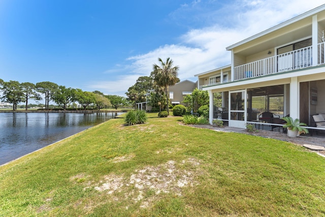 view of yard featuring a water view, a balcony, and a sunroom