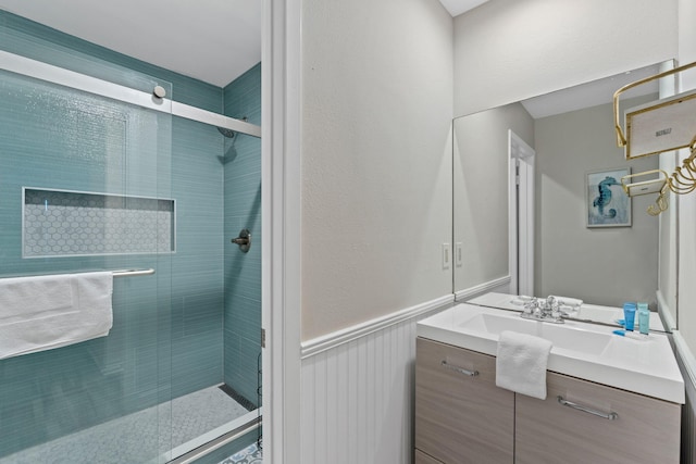 full bathroom with a wainscoted wall, a shower stall, and vanity