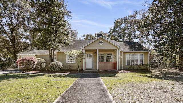 view of front of property with a shingled roof, fence, a chimney, and a front lawn