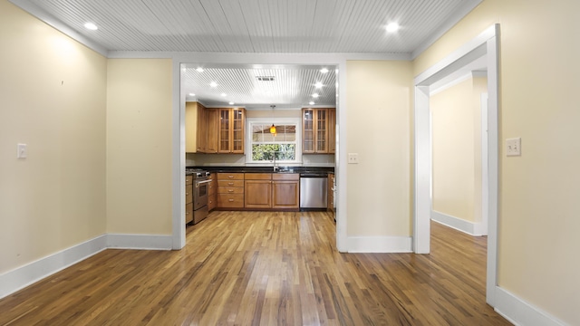516 College Ave, Defuniak Springs, FL 32435 - kitchen with stainless steel appliances, baseboards, light wood-style floors, brown cabinets, and dark countertops