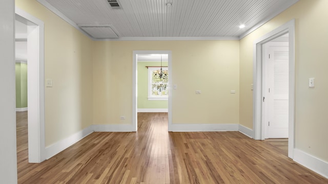 516 College Ave, Defuniak Springs, FL 32435 - empty room with a chandelier, wood finished floors, visible vents, baseboards, and ornamental molding