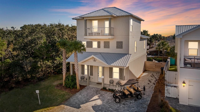 view of front of property featuring a balcony, a gate, fence, and metal roof