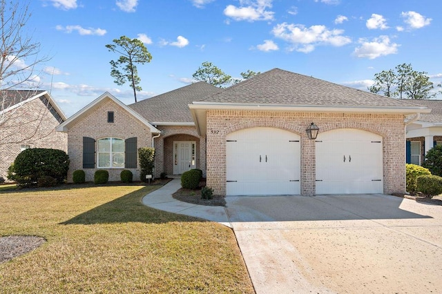 french provincial home with a garage, a shingled roof, brick siding, concrete driveway, and a front lawn