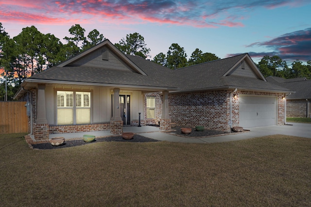 view of front of home with a garage, driveway, a lawn, roof with shingles, and brick siding