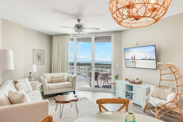 living area featuring expansive windows, ceiling fan, and light wood finished floors