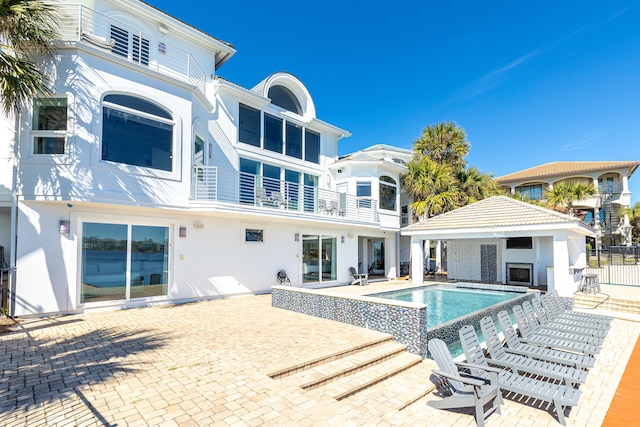 rear view of property with a patio, a balcony, fence, a fenced in pool, and stucco siding