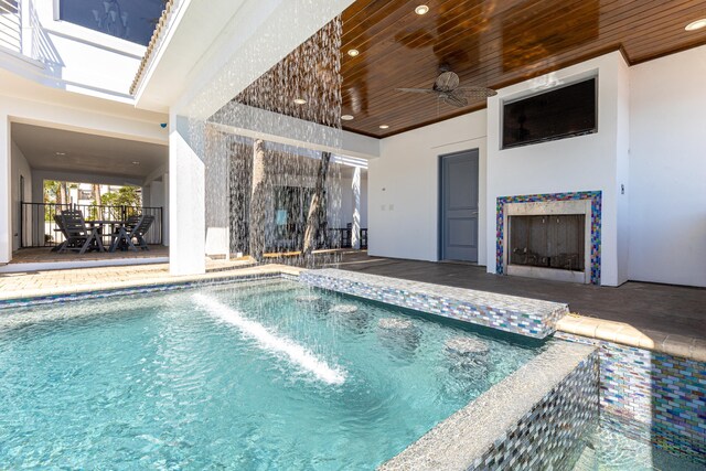 pool with a patio area, a fireplace, a ceiling fan, and outdoor dining space