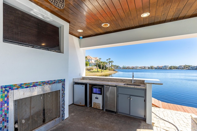 view of patio / terrace with a water view, a sink, and area for grilling