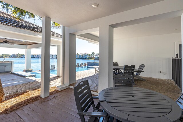 view of patio with outdoor dining space, a water view, and an outdoor pool