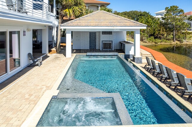 view of pool featuring an outbuilding, a patio area, and a pool with connected hot tub