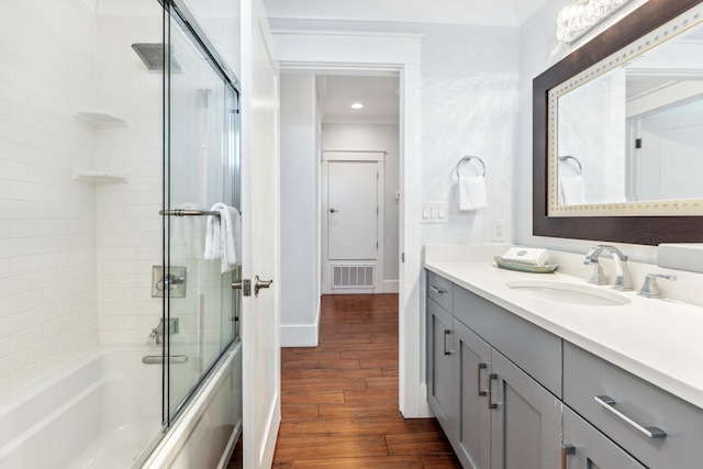 bathroom featuring baseboards, visible vents, enclosed tub / shower combo, wood finished floors, and vanity