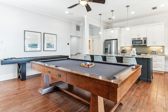 rec room with baseboards, visible vents, crown molding, and wood finished floors