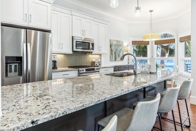 kitchen featuring backsplash, appliances with stainless steel finishes, ornamental molding, a sink, and plenty of natural light