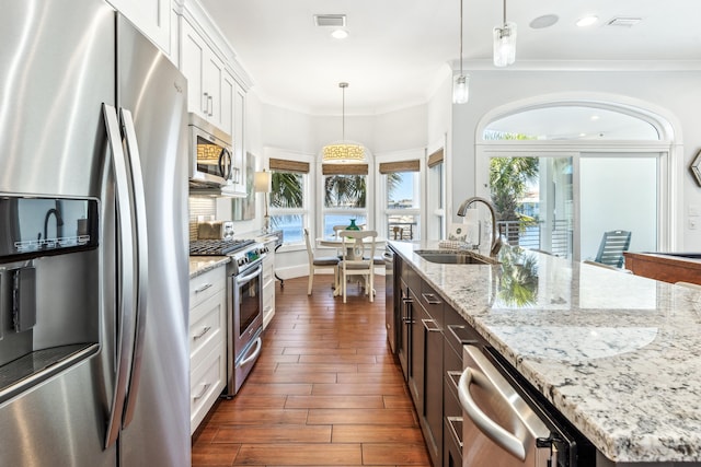 kitchen featuring stainless steel appliances, dark wood-type flooring, a sink, visible vents, and crown molding