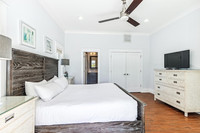 bedroom featuring dark wood finished floors, visible vents, a ceiling fan, ornamental molding, and ensuite bath