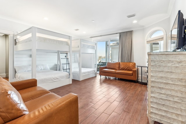 bedroom with multiple windows, crown molding, visible vents, and wood finished floors