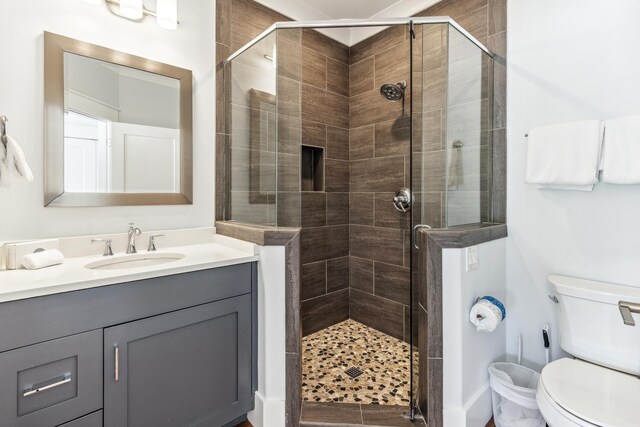 full bath featuring toilet, a shower stall, and vanity