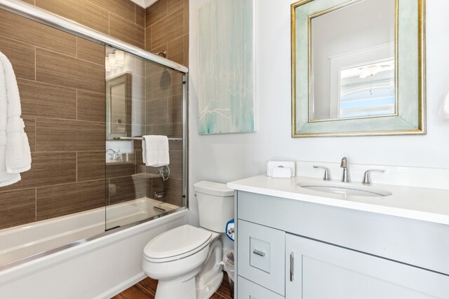 full bath featuring toilet, combined bath / shower with glass door, and vanity