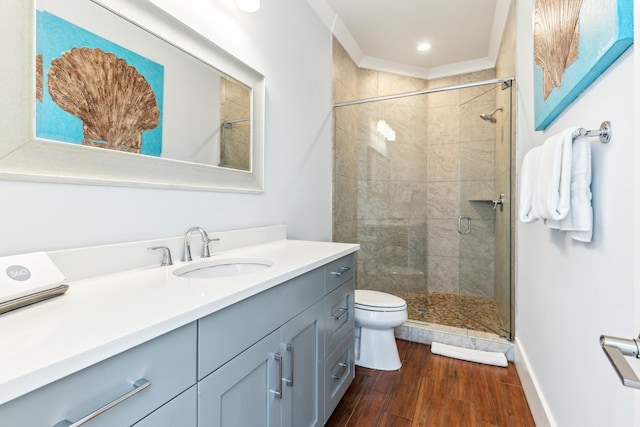 bathroom featuring toilet, a stall shower, wood finished floors, and vanity