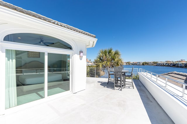 view of patio featuring ceiling fan, a water view, and a balcony