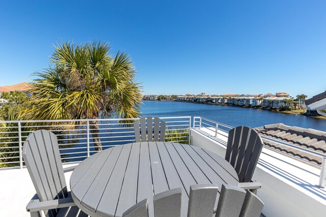 wooden terrace with a water view and outdoor dining space